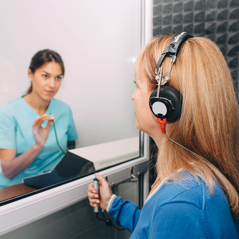 Woman inside audiology booth testing her hearing
