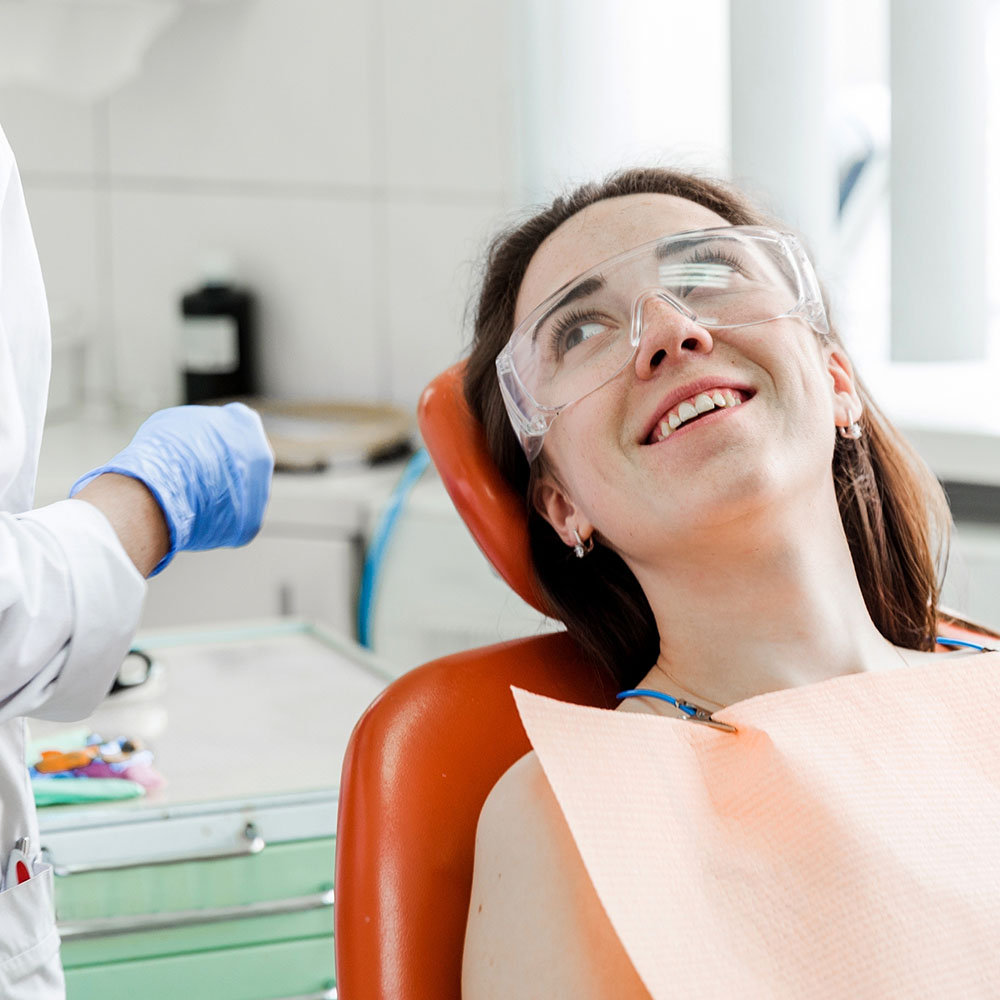 Woman on dentist's chair with protective eyeware on